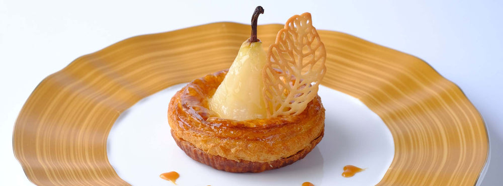 Vanilla-Poached Pear Tart on a white and gold plate from the Daily Garnish Holiday menu